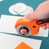 Cutter rotatif Ø 45 mm, manche ergonomique orange et noir, livré avec 5 lames de rechange, parfait pour la découpe précise de divers matériaux.