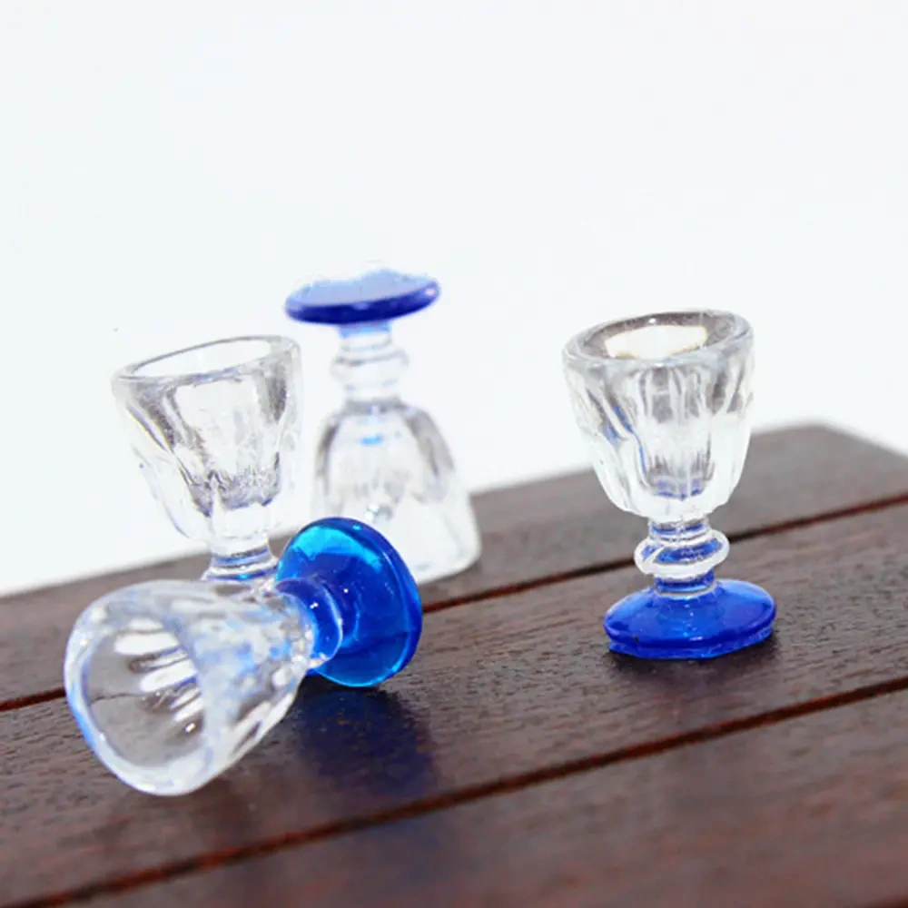 Verres à pied miniatures bleus disposés sur une table de maison de poupée