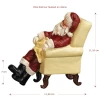 Figurine Père Noël en résine endormi sur fauteuil.