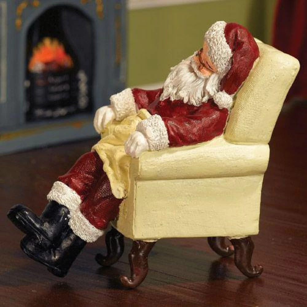 Figurine Père Noël en résine endormi sur fauteuil.