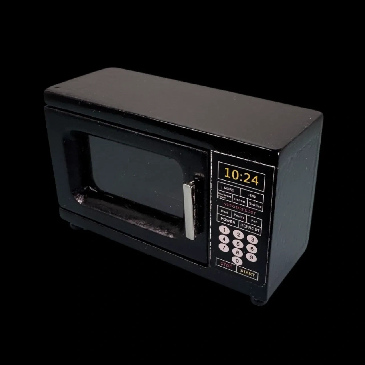 Micro-ondes miniature noir en bois présenté sur fond noir