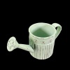 Arrosoir miniature vert pâle en métal vieilli vu de dessus sur fond noir