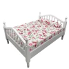 Lit miniature blanc avec matelas fleuri sur fond blanc