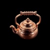 Bouilloire miniature cuivrée en métal sur fond noir
