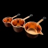 Trois casseroles miniatures cuivrées manches noirs vues séparément