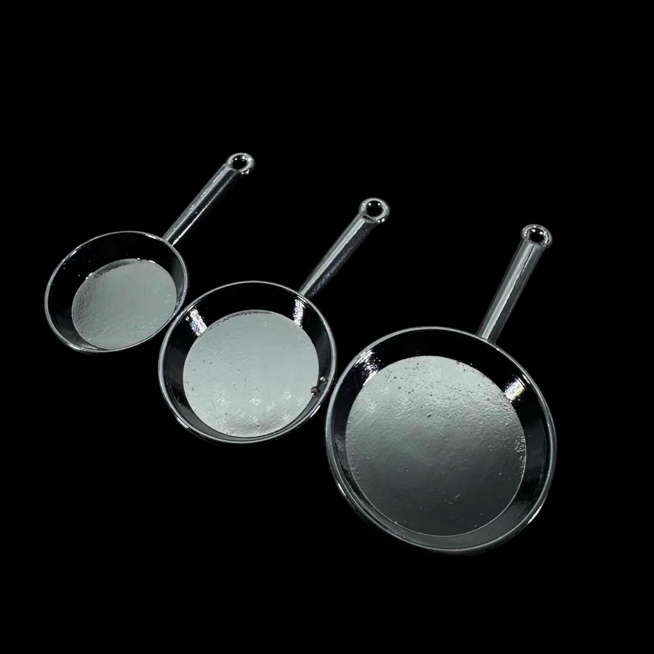 Lot de 3 poêles miniatures noires en métal présenté sur fond noir
