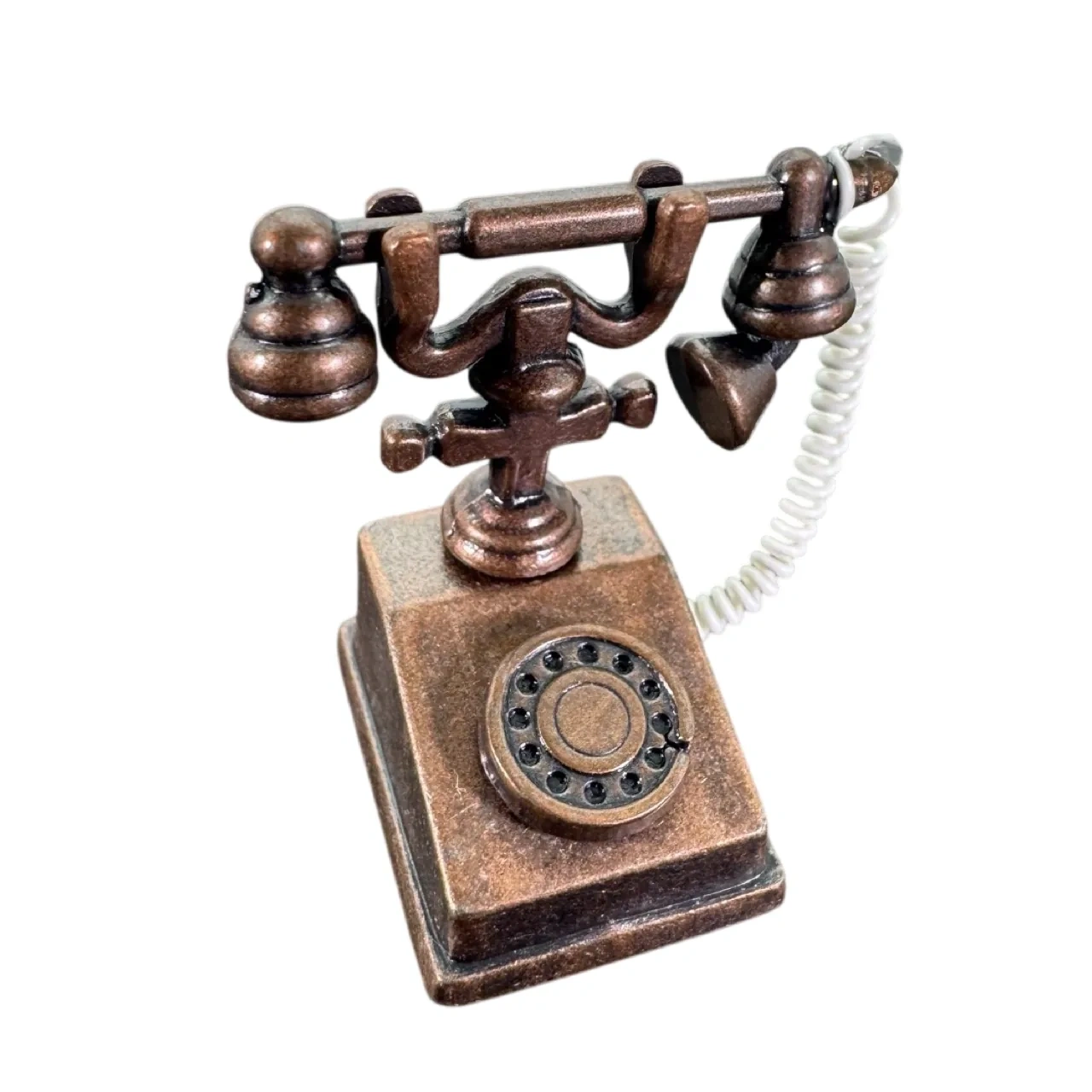 Téléphone rétro miniature en métal couleur bronze sur fond blanc