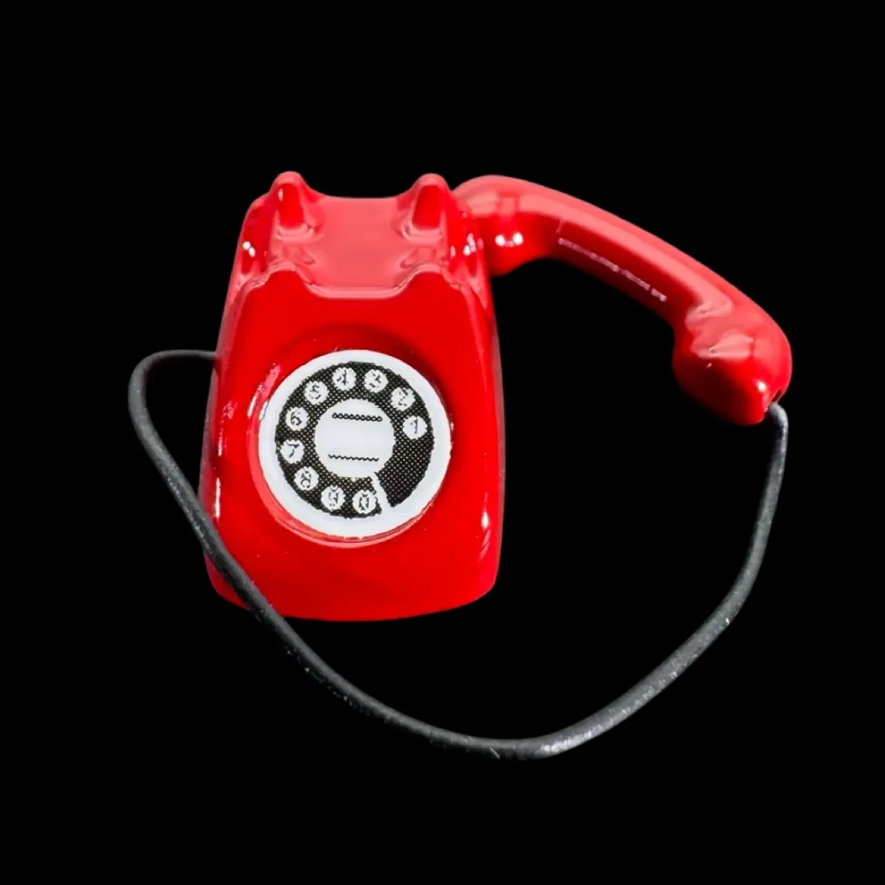 Téléphone rouge miniature avec combiné amovible posé à côté